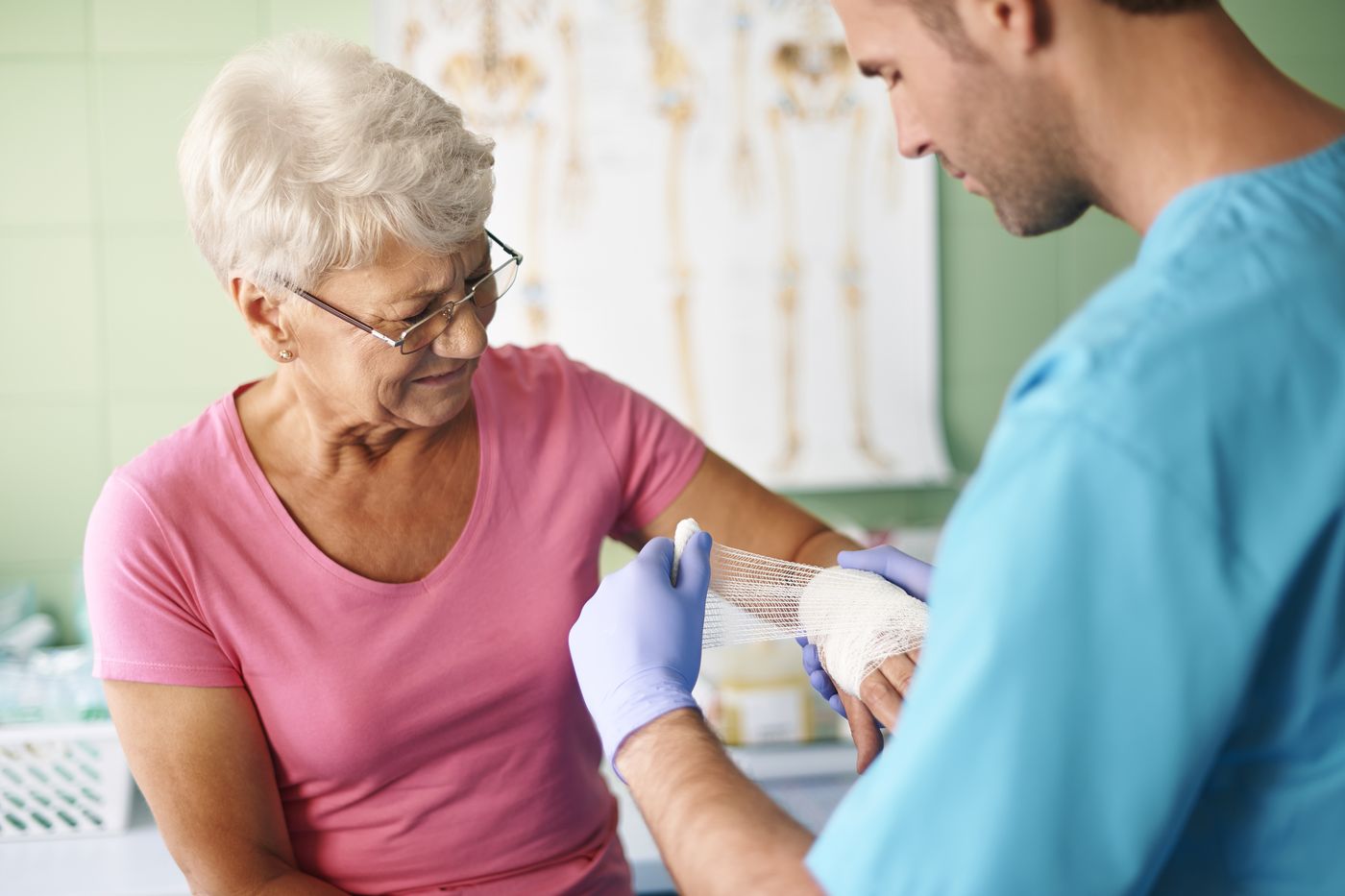A clinician bandaging an older woman's wrist and hand