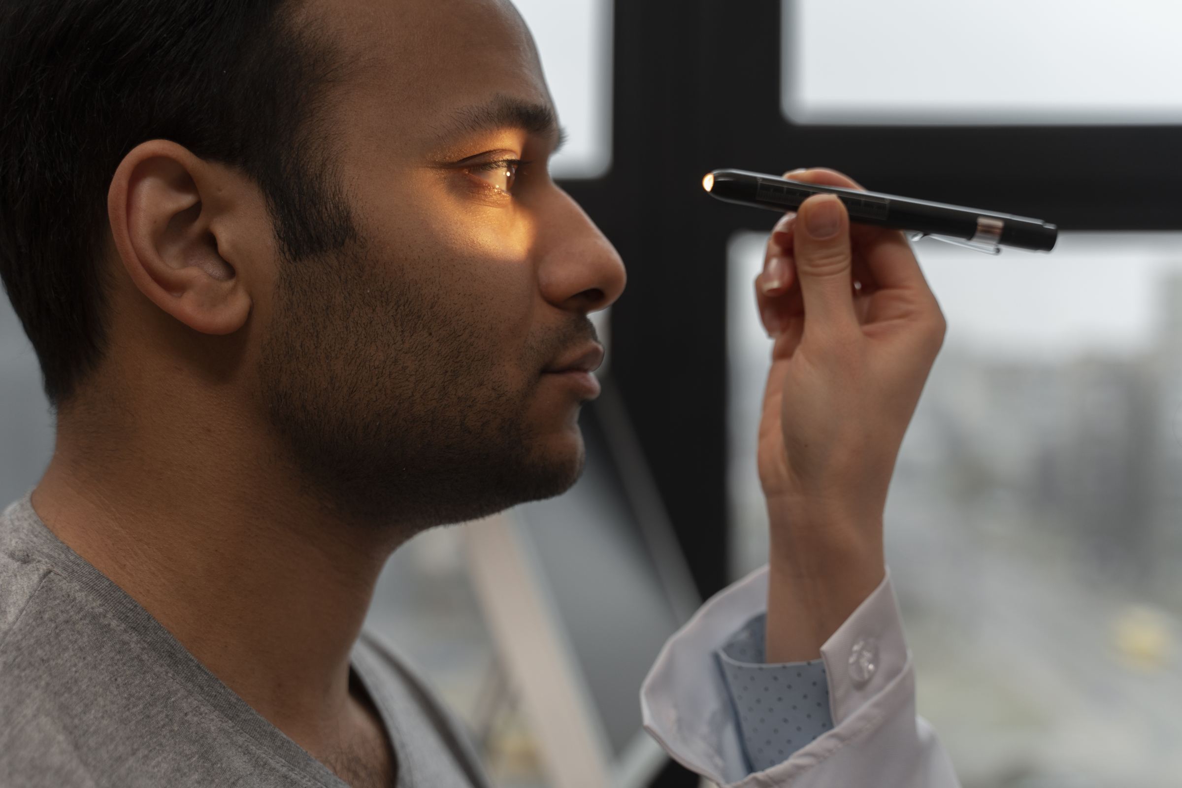 A clinician shining a penlight to check a man's eyes